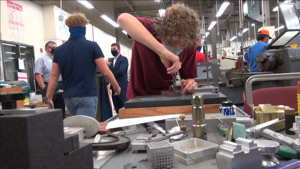 a student works on a machining project in the classroom. Everyone is wearing a facemask